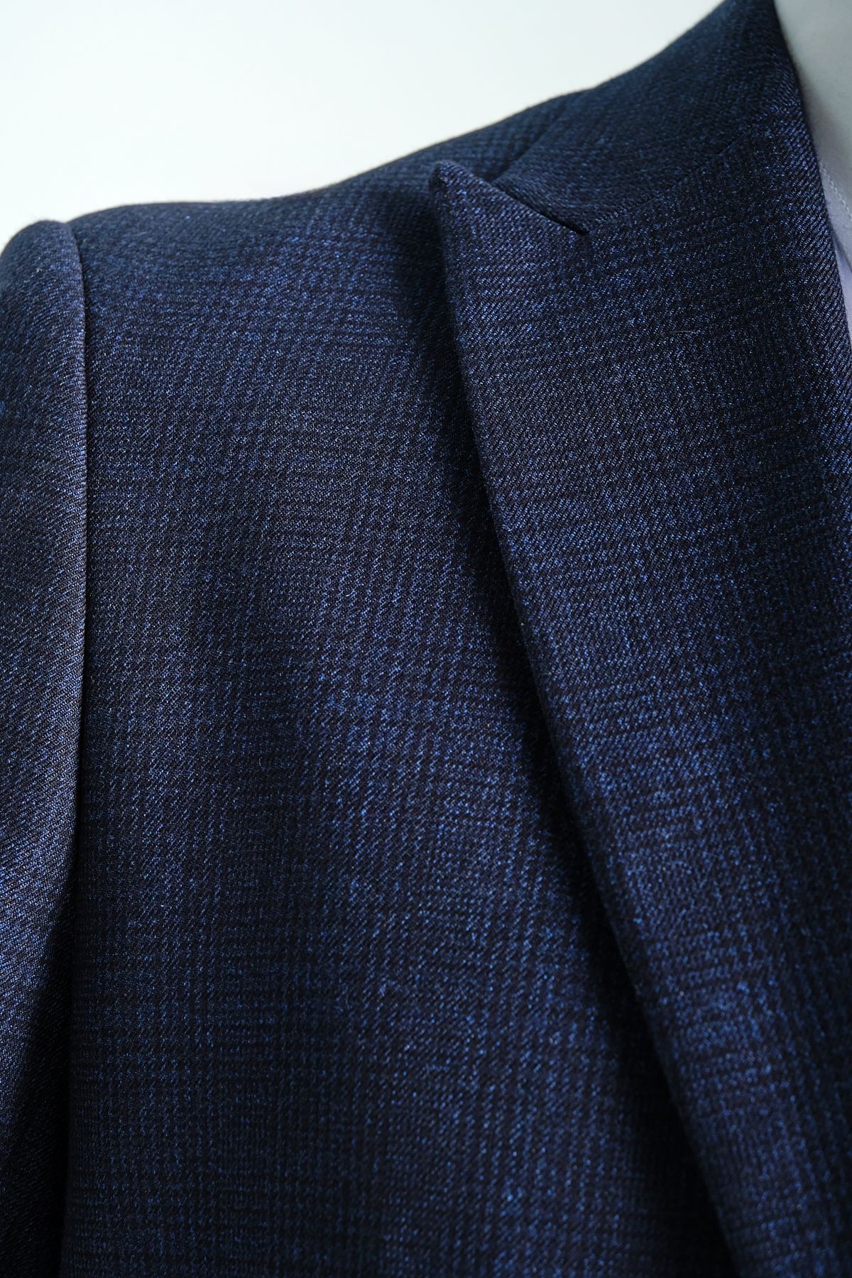 Close-up of dark blue textured suit fabric, showcasing high-quality material and detailed pattern