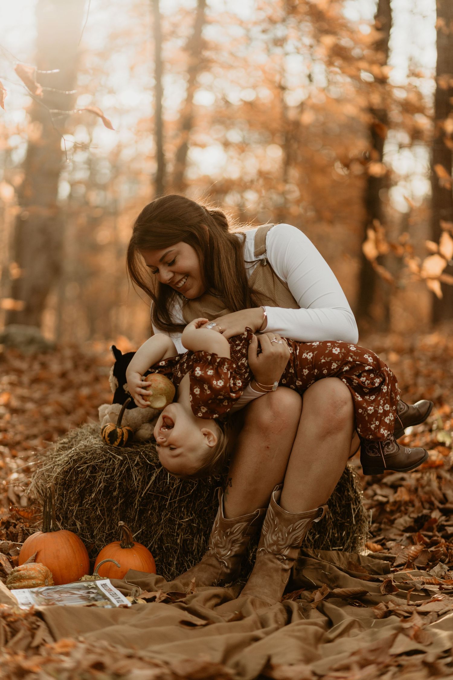 Autumn scene with pumpkins and a playful moment on a hay bale in warm golden light.
