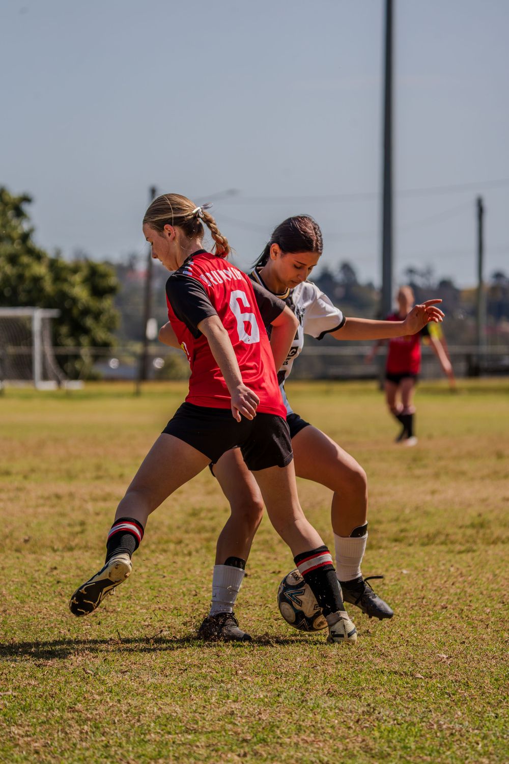 Two soccer players battling for ball possession during an intense match on a grass field.