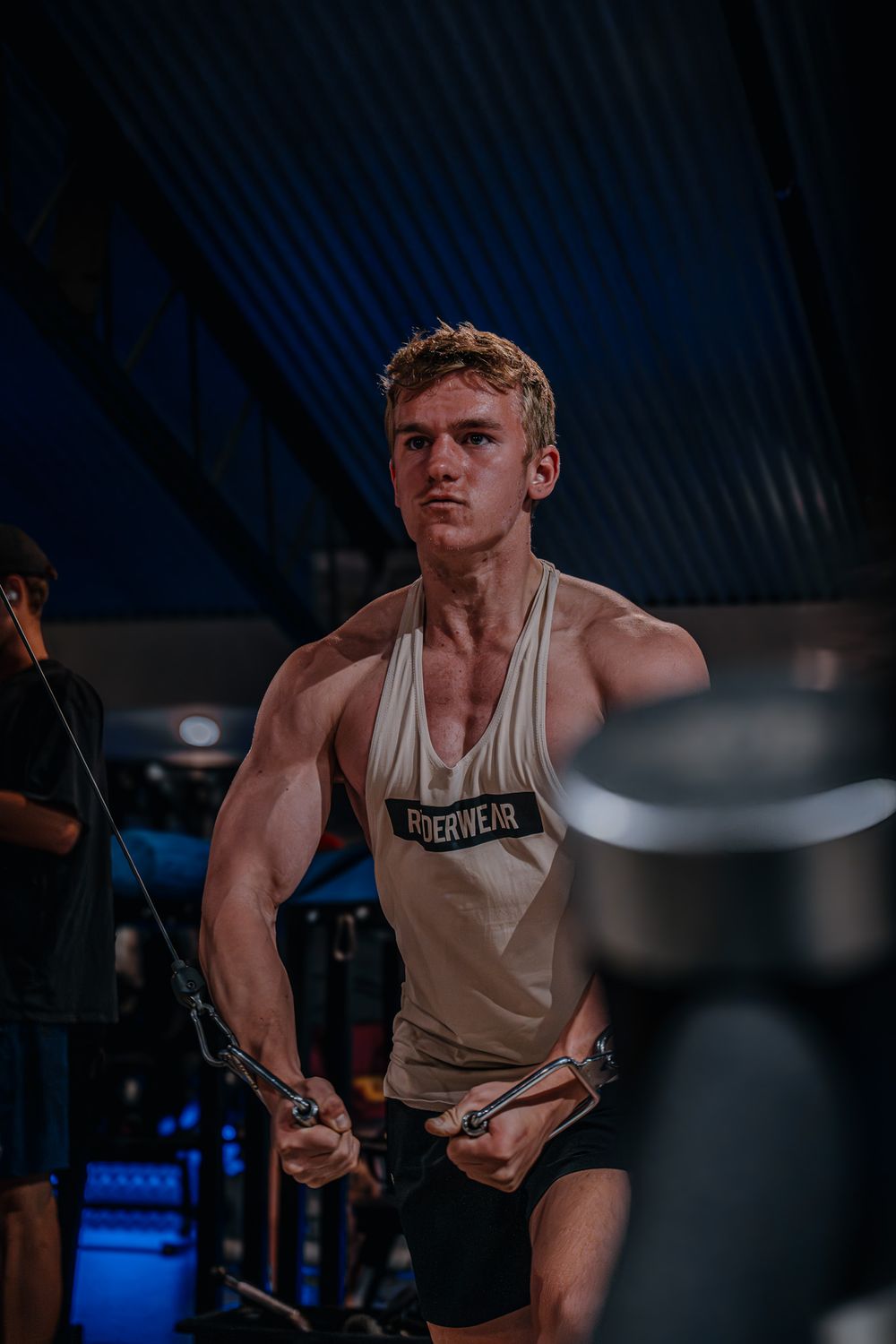 An athlete performing cable exercises in a dimly lit gym setting.