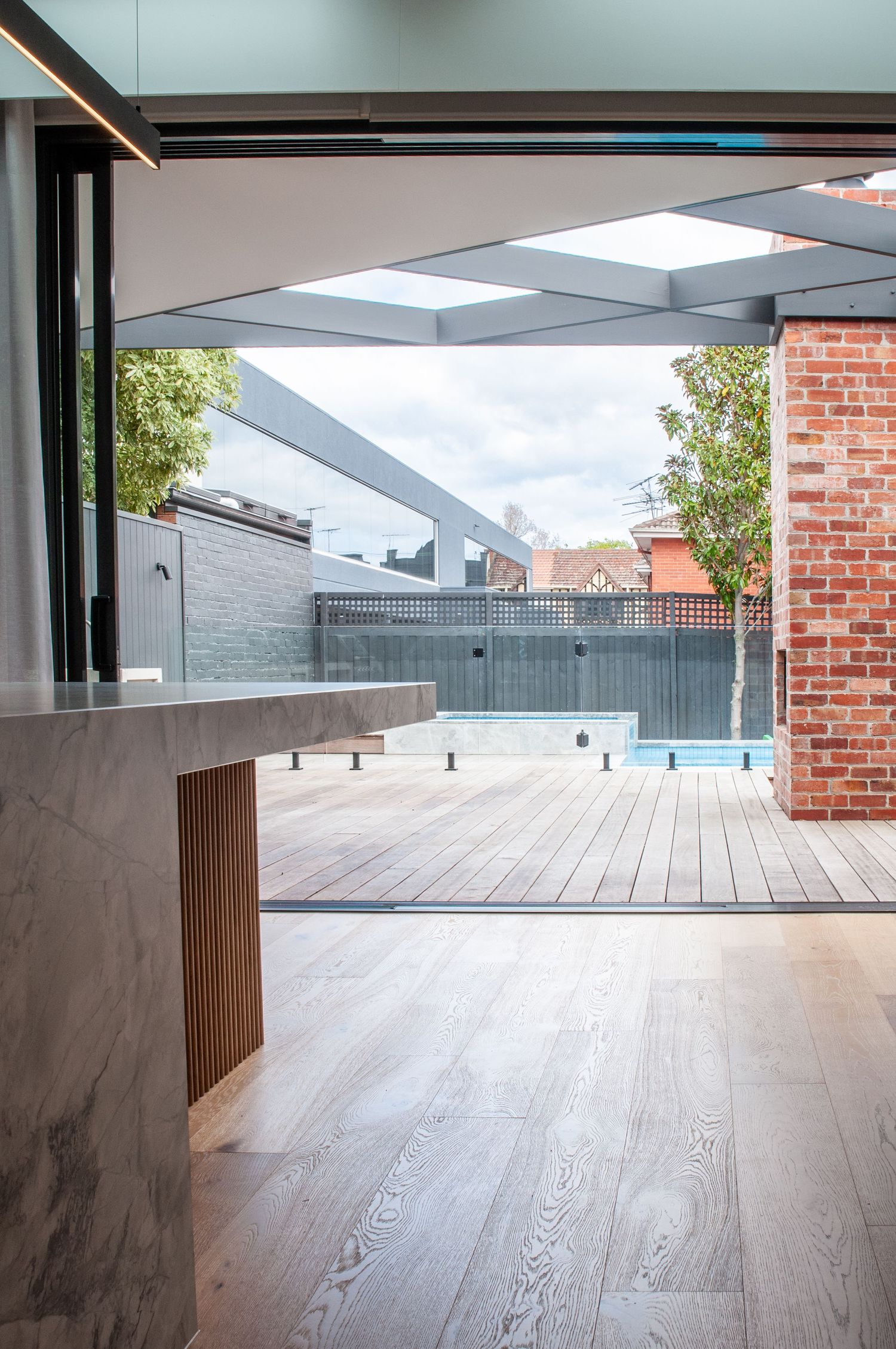 Open-concept kitchen extending to wooden deck and pool area through large sliding glass doors.