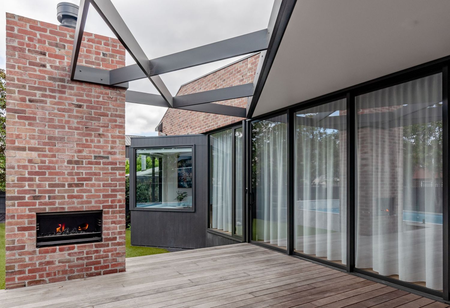 Covered outdoor patio with brick walls, glass sliding doors, and built-in fireplace.