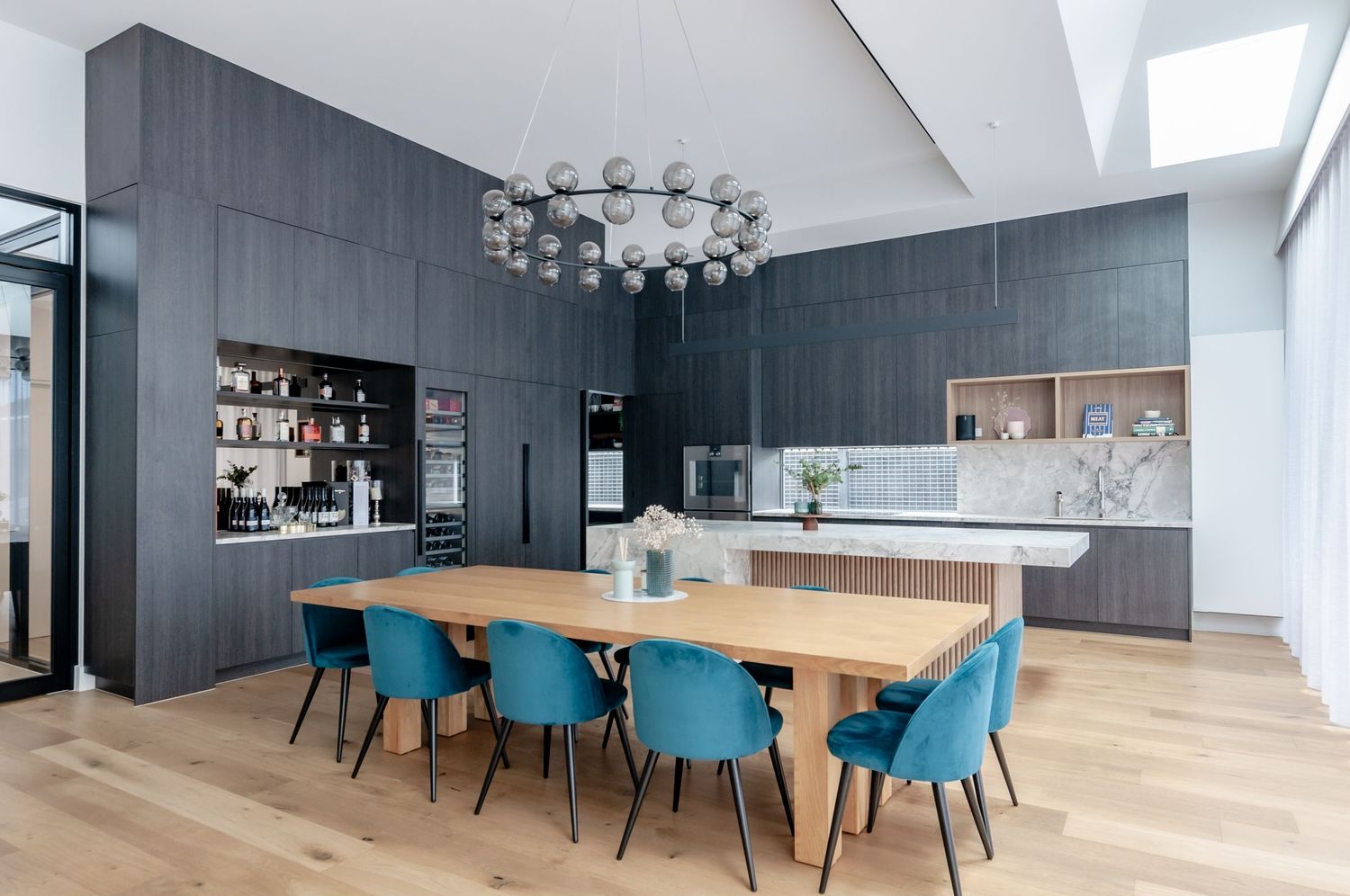 Contemporary dining area with blue chairs and dark wood cabinets in an open concept space.