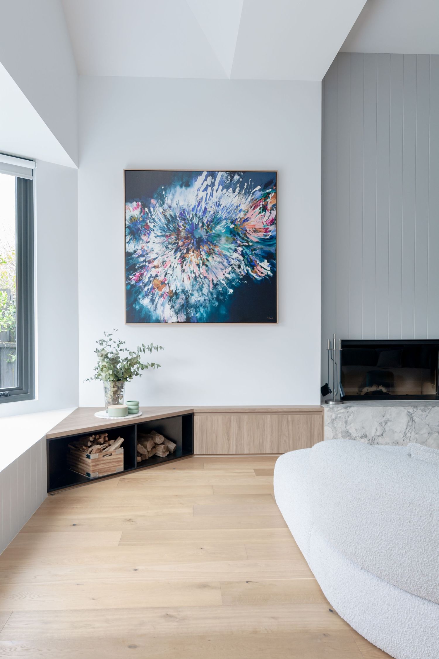 Minimalist living space with blue abstract art, built-in storage, and light wood flooring.