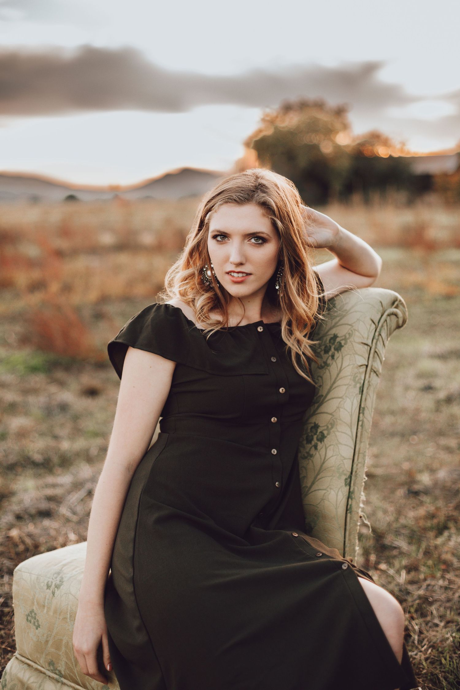 Rustic senior photography in Rocklin, CA. Young woman in a black dress posing outdoors with golden hour light.