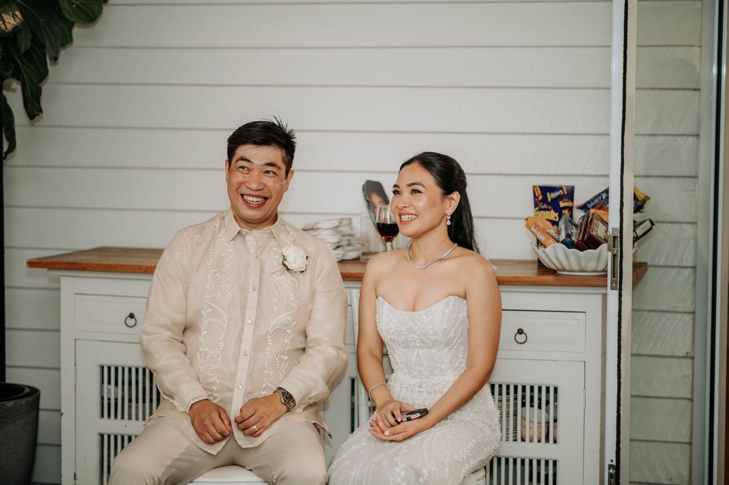 A couple shares a joyful moment while seated together during their wedding reception.