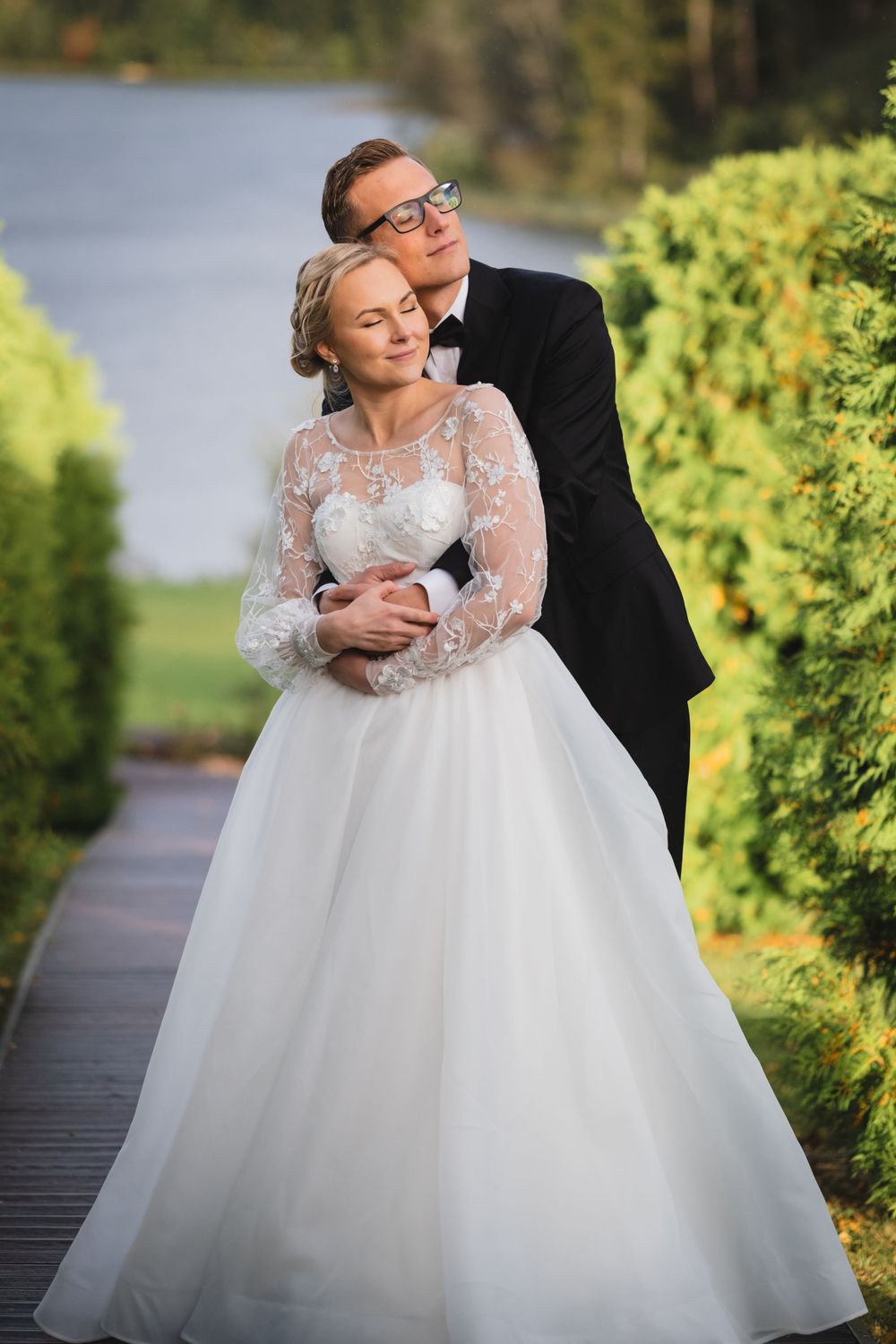 Intimate wedding portrait on a garden path with the bride wearing a lace-sleeved gown.
