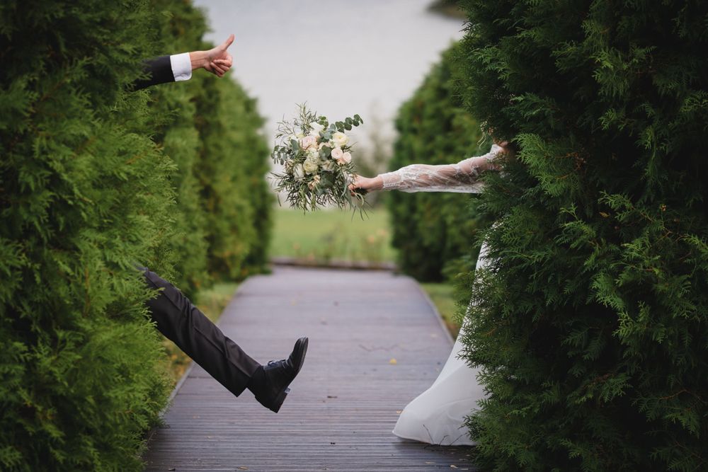 Creative wedding photo with couple appearing to float horizontally between hedges.
