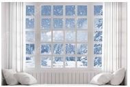 A window with white trim looks out onto a snowy winter landscape with a bright blue sky.