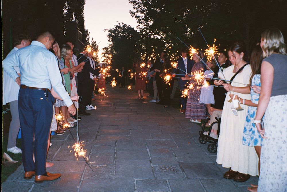 Wedding guests lining a pathway holding sparklers during an evening send-off celebration.