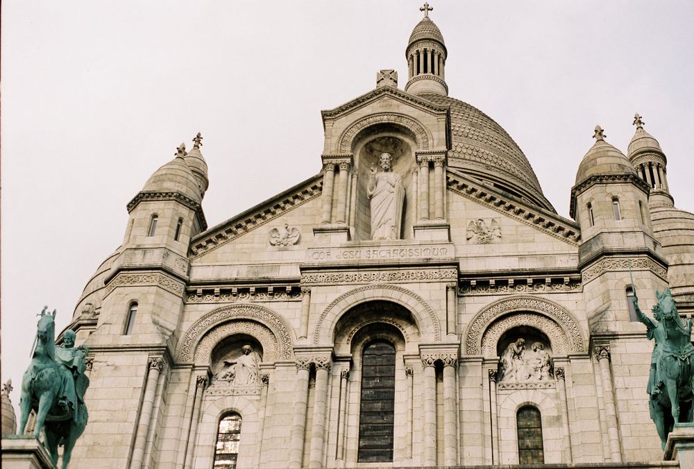 Front facade of Sacre-Coeur Basilica in Paris featuring Roman-Byzantine architecture with equestrian statues.