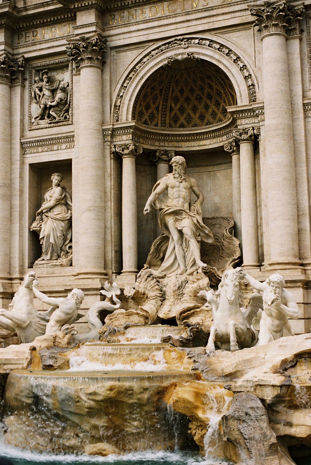 The ornate Trevi Fountain in Rome features Neptune statue surrounded by mythological figures and cascading water.
