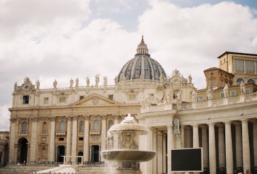 St. Peters Basilica in Vatican City showcases its iconic dome and grand colonnade under a partly cloudy sky.