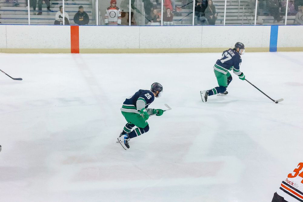 Hockey players skate and practice drills on an indoor ice rink during a training session.
