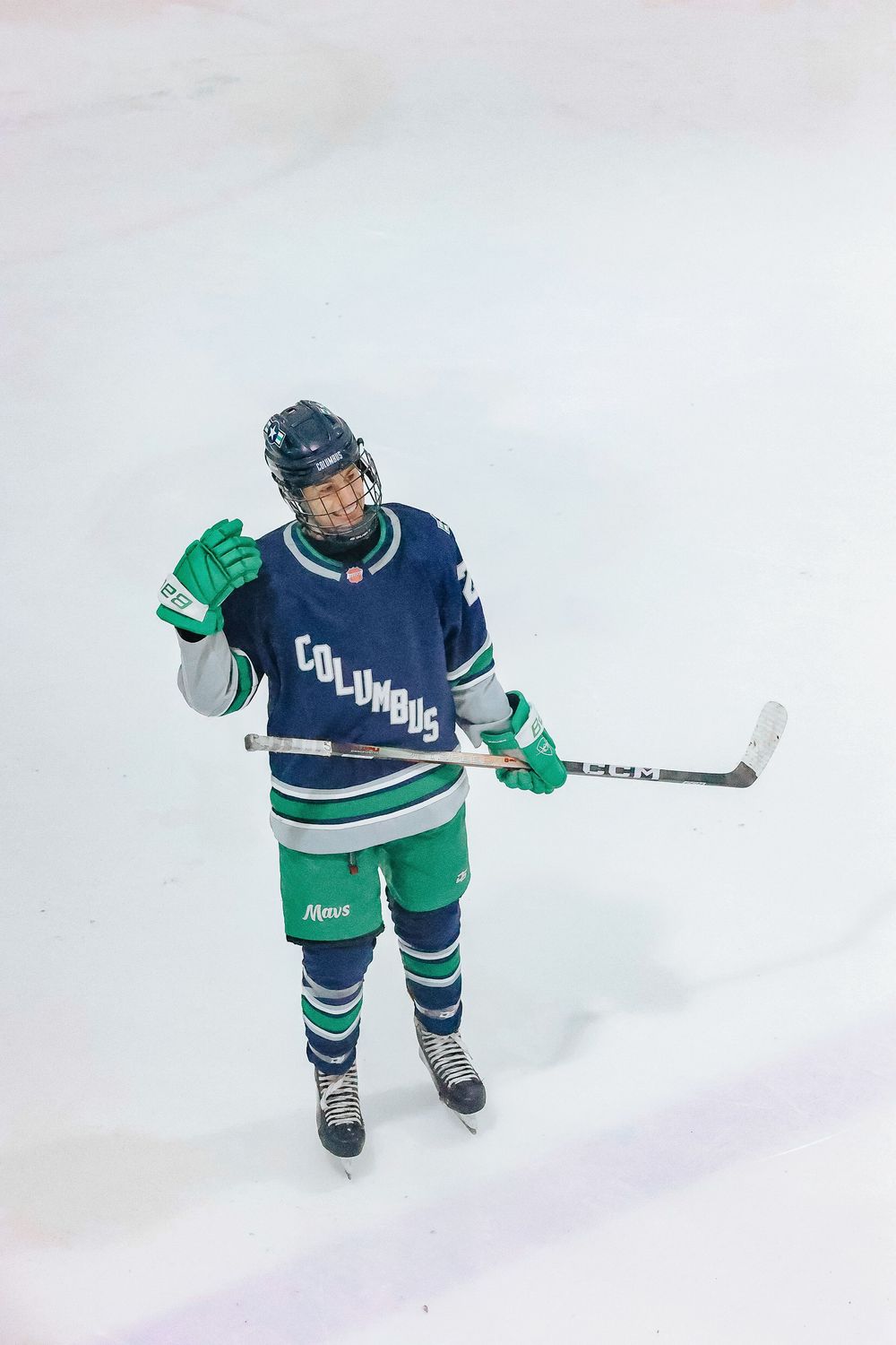 Hockey player in Columbia uniform stands on ice holding stick during game.