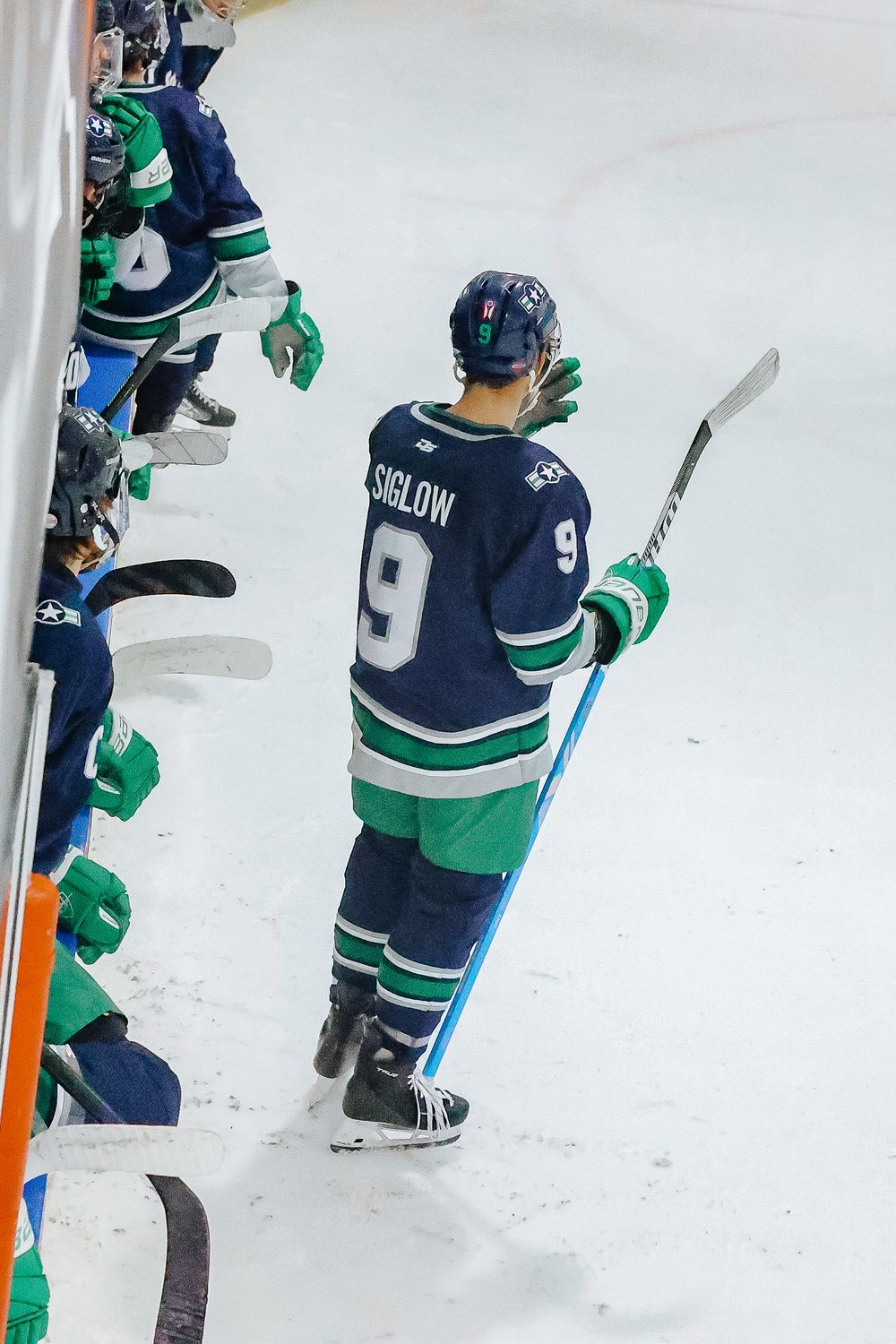 Hockey players from opposing teams face off near the boards during an intense game moment.