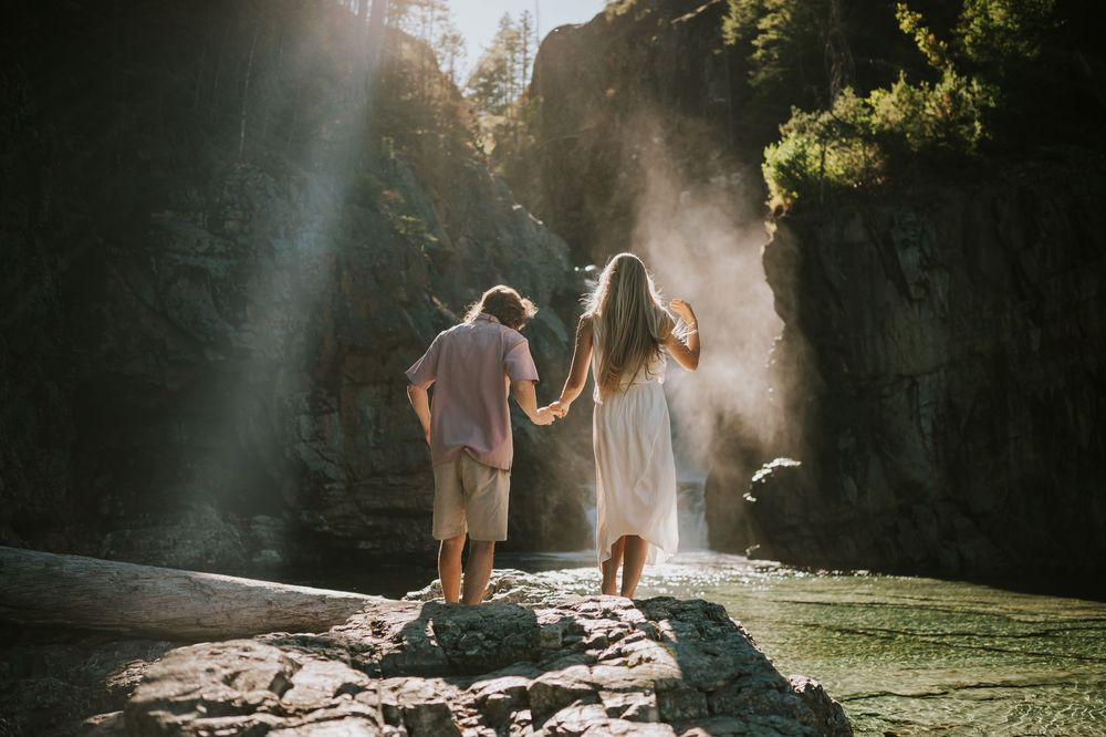 Couple adventure photoshoot session at Myra Falls on Vancouver island taken by professional photographer of couple walking to waterfall