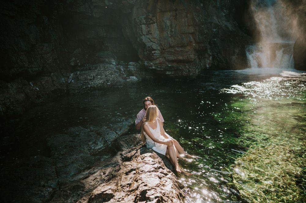 Couple adventure photoshoot session at Myra Falls on Vancouver island taken by professional photographer of couple sitting by waterfall