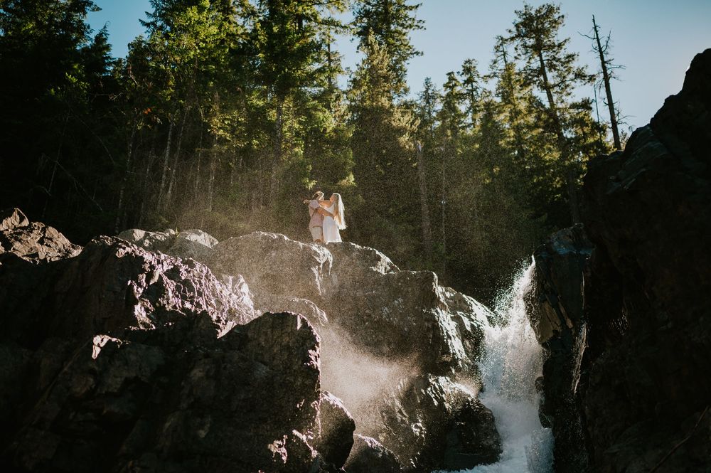 Couple adventure photoshoot session at Myra Falls on Vancouver island taken by professional photographer of couple dancing by waterfall