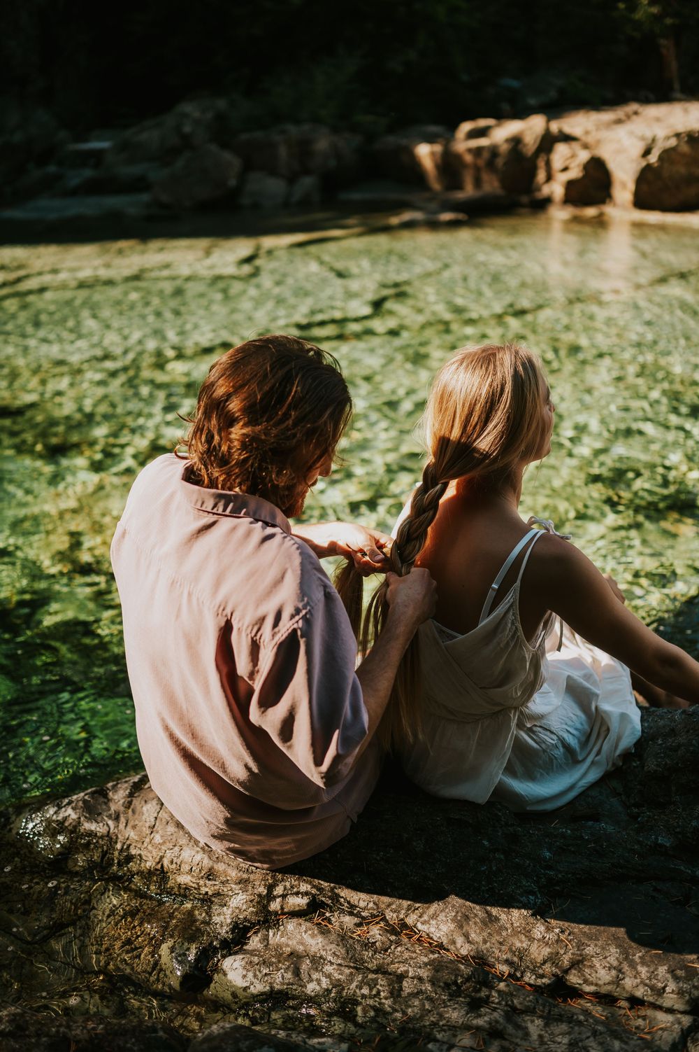 Couple adventure photoshoot session at Myra Falls on Vancouver island taken by professional photographer of couple braiding hair