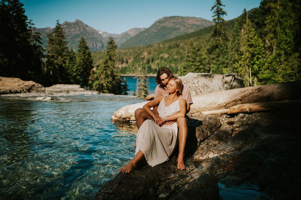 Couple adventure photoshoot session at Myra Falls on Vancouver island taken by professional photographer of couple snuggling by lake