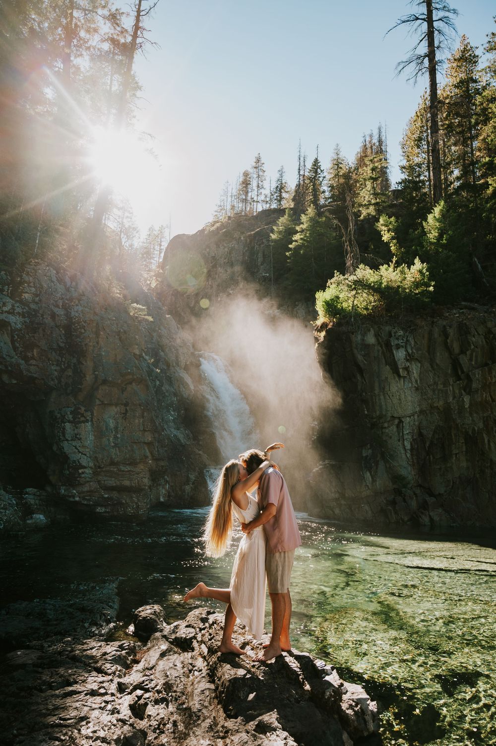 Couple adventure photoshoot session at Myra Falls on Vancouver island taken by professional photographer of couple snuggling by waterfall