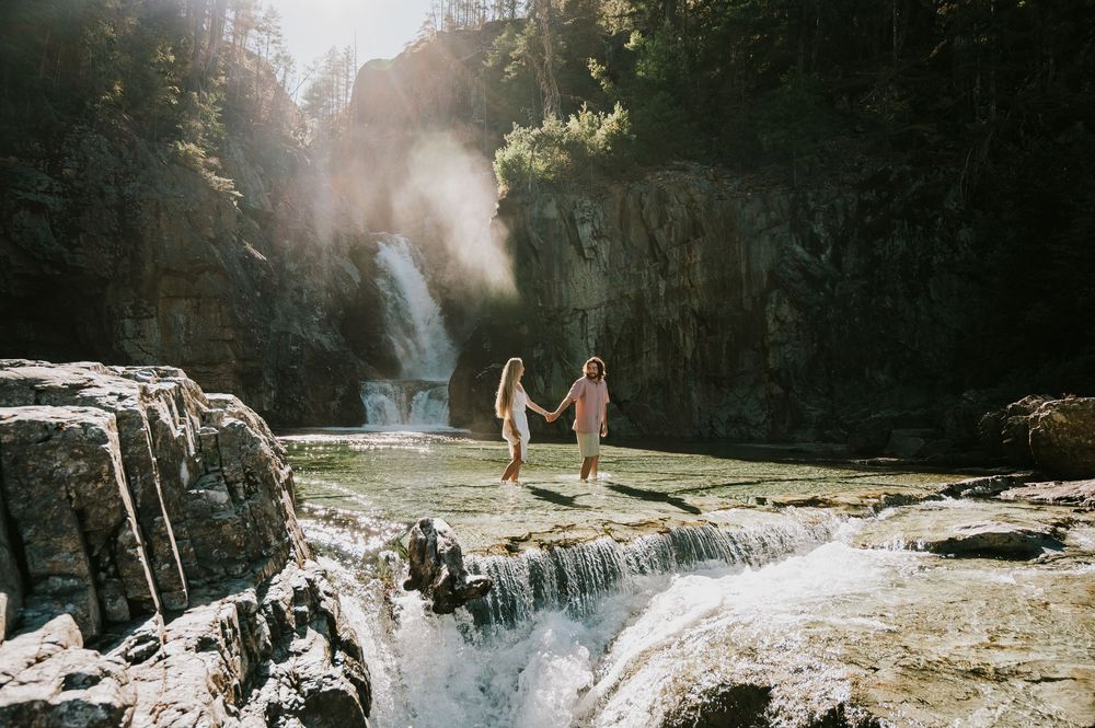 Couple adventure photoshoot session at Myra Falls on Vancouver island taken by professional photographer of couple walking through waterfall