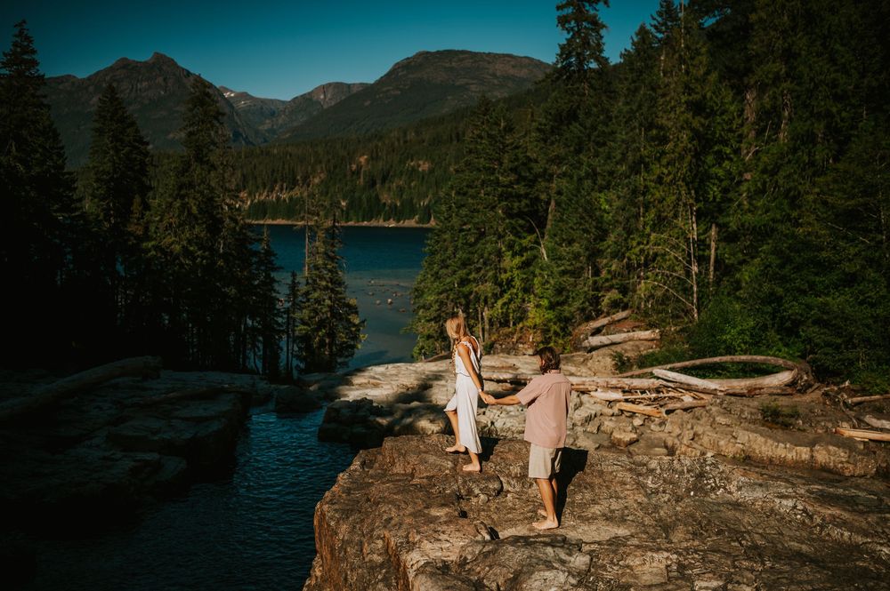 Couple adventure photoshoot session at Myra Falls on Vancouver island taken by professional photographer of couple walking down lake