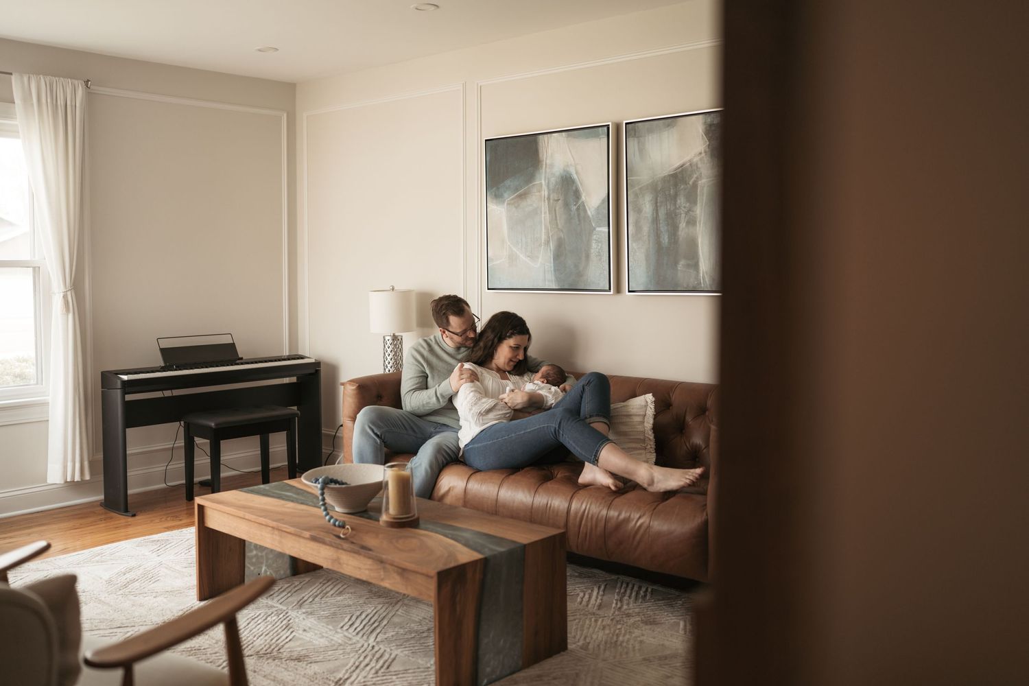 A person lounges on a brown leather couch in a minimalist living room with white walls and natural light.