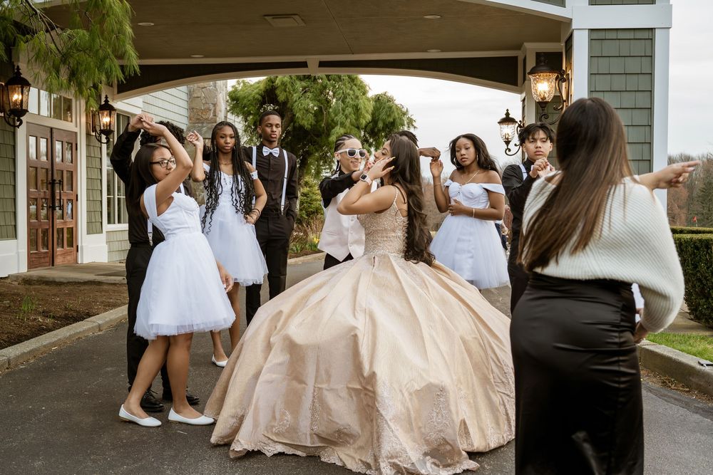 A group of people in formal attire gather outside a building during a wedding celebration.
