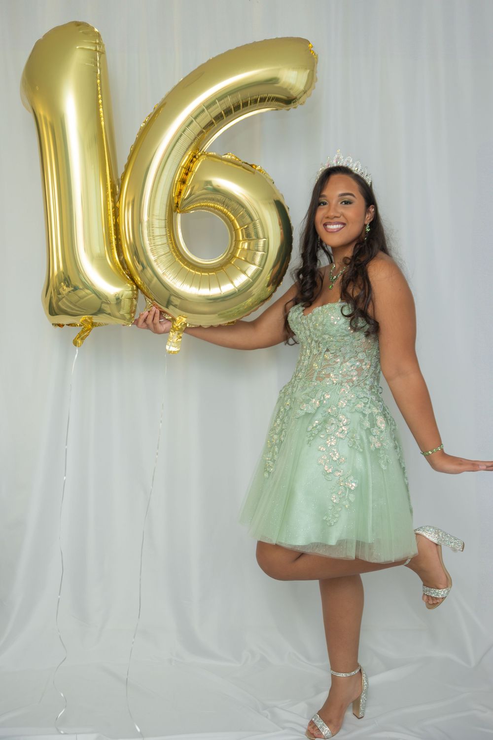 A series of photos showing someone in a sparkly mint dress striking fun poses with gold balloon letters.