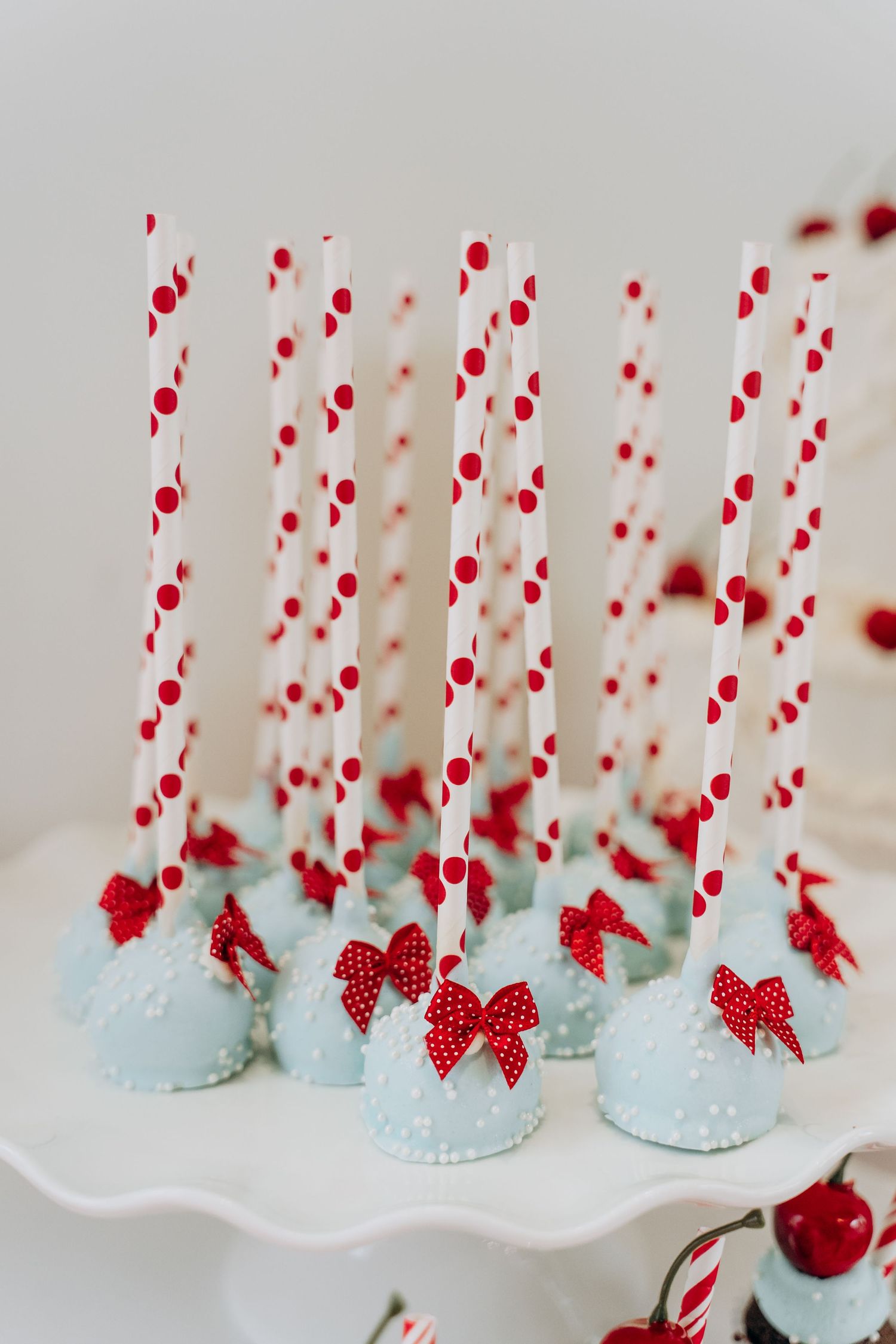 Glass milk bottles decorated with red polka dot straws and bows create a charming vintage party display.