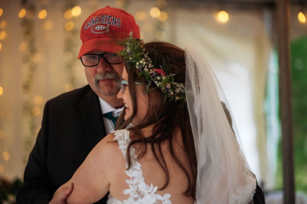 Bride dancing with father wearing red Montreal Canadiens cap at wedding.