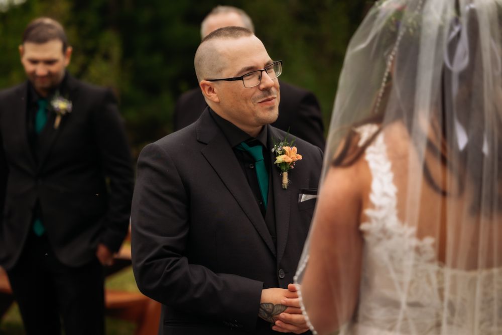 Groom gazing lovingly at bride during outdoor wedding ceremony exchange.