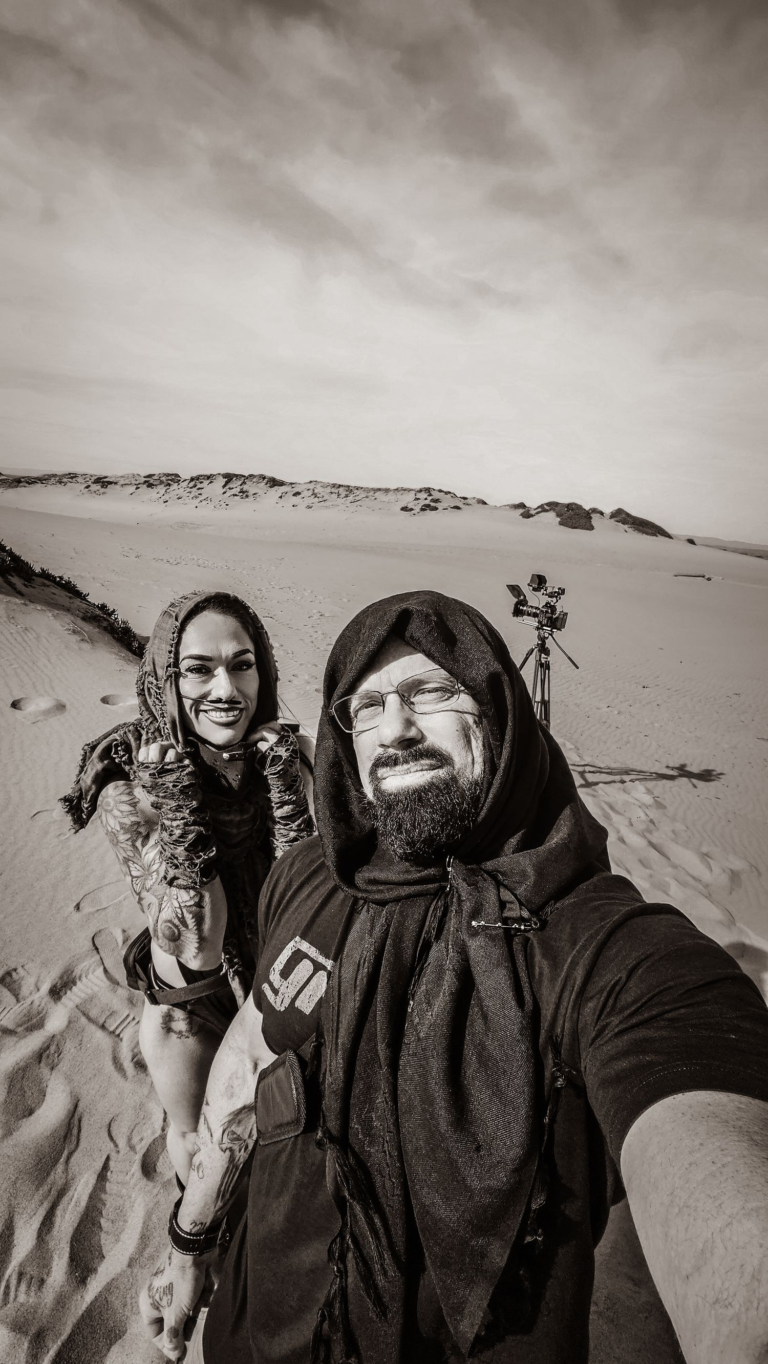 A black and white photo series showing people in dark hooded jackets with a dog in a snowy winter landscape.