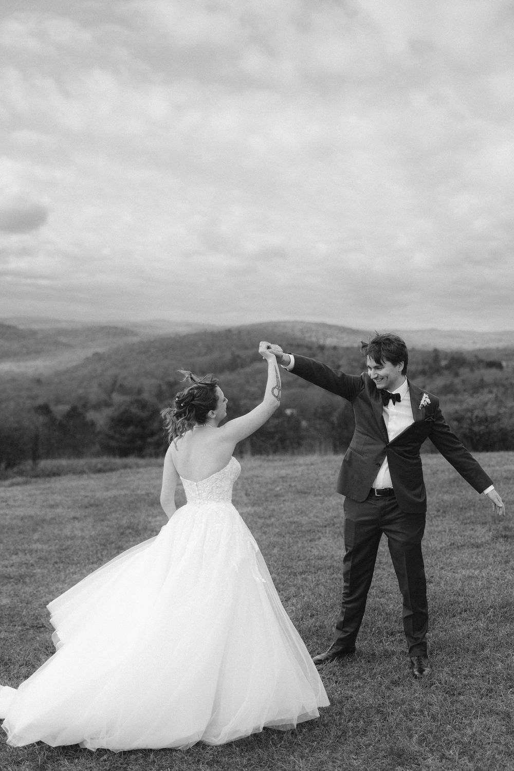 Black and white wedding photos of a couple dancing and twirling in a scenic mountain landscape.