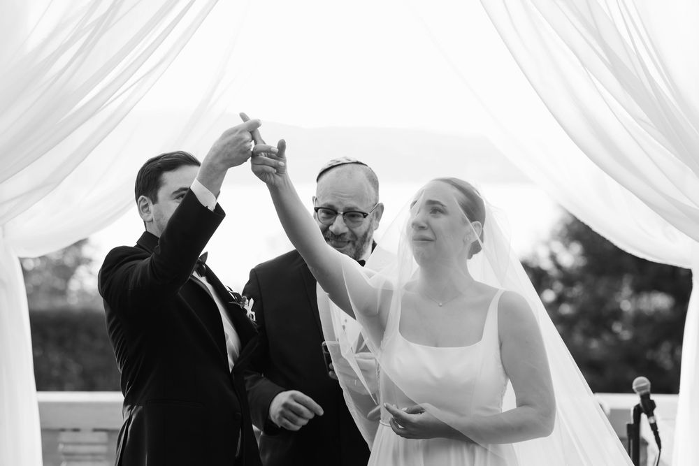 A celebratory moment during an outdoor wedding ceremony under a white draped canopy.