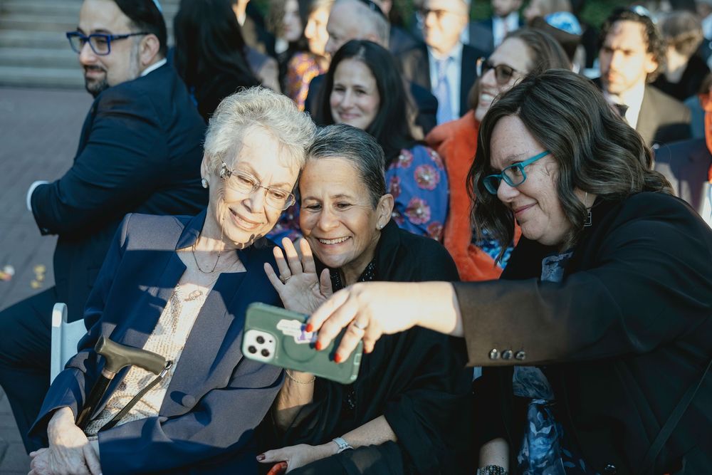 Guests at a formal event share joyful laughter while seated in a crowd.