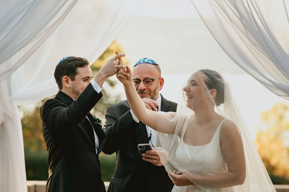 A celebratory toast moment during an outdoor wedding ceremony under flowing white fabric.