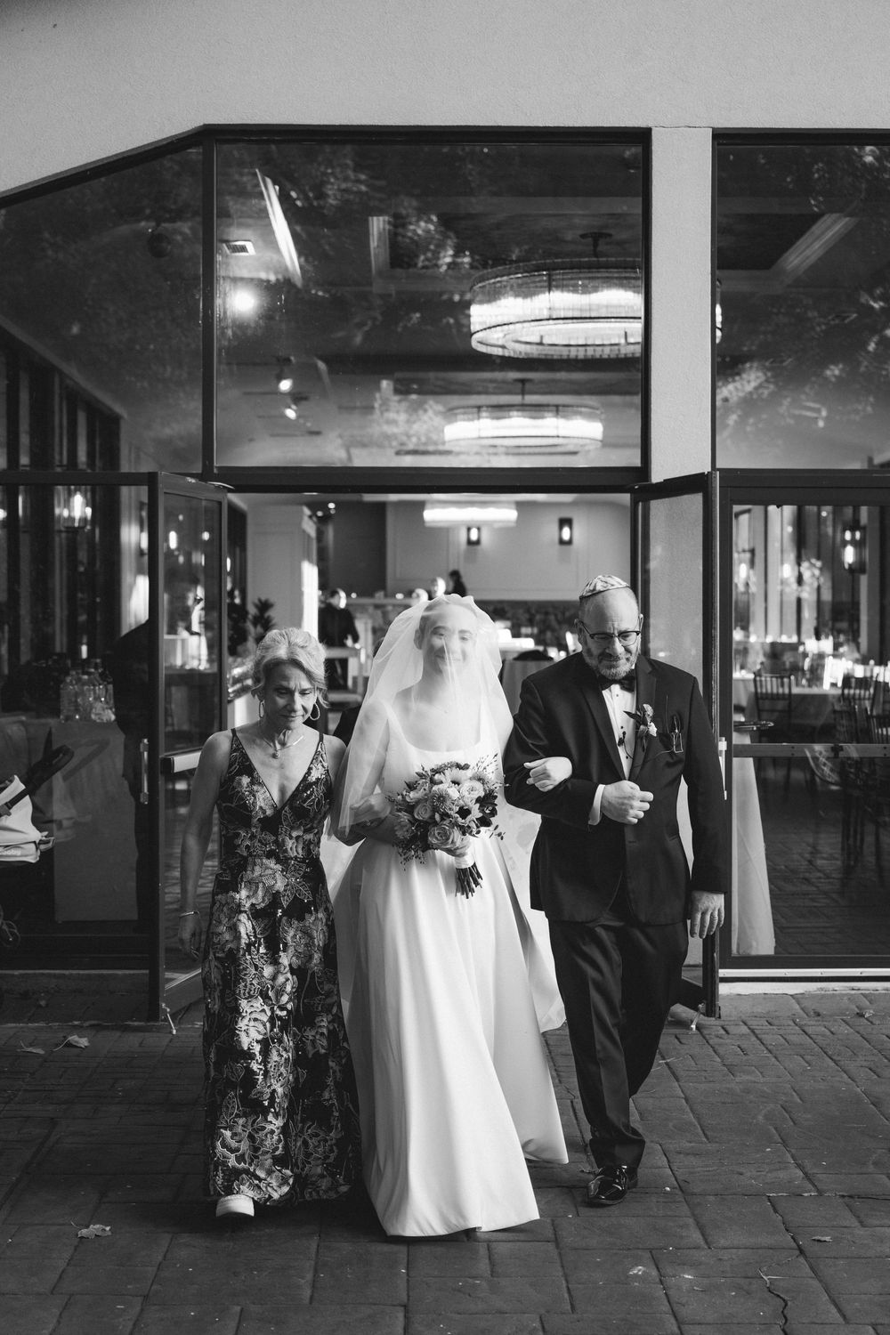 A sequence of black and white wedding photos showing guests and wedding party members outside a venue entrance.