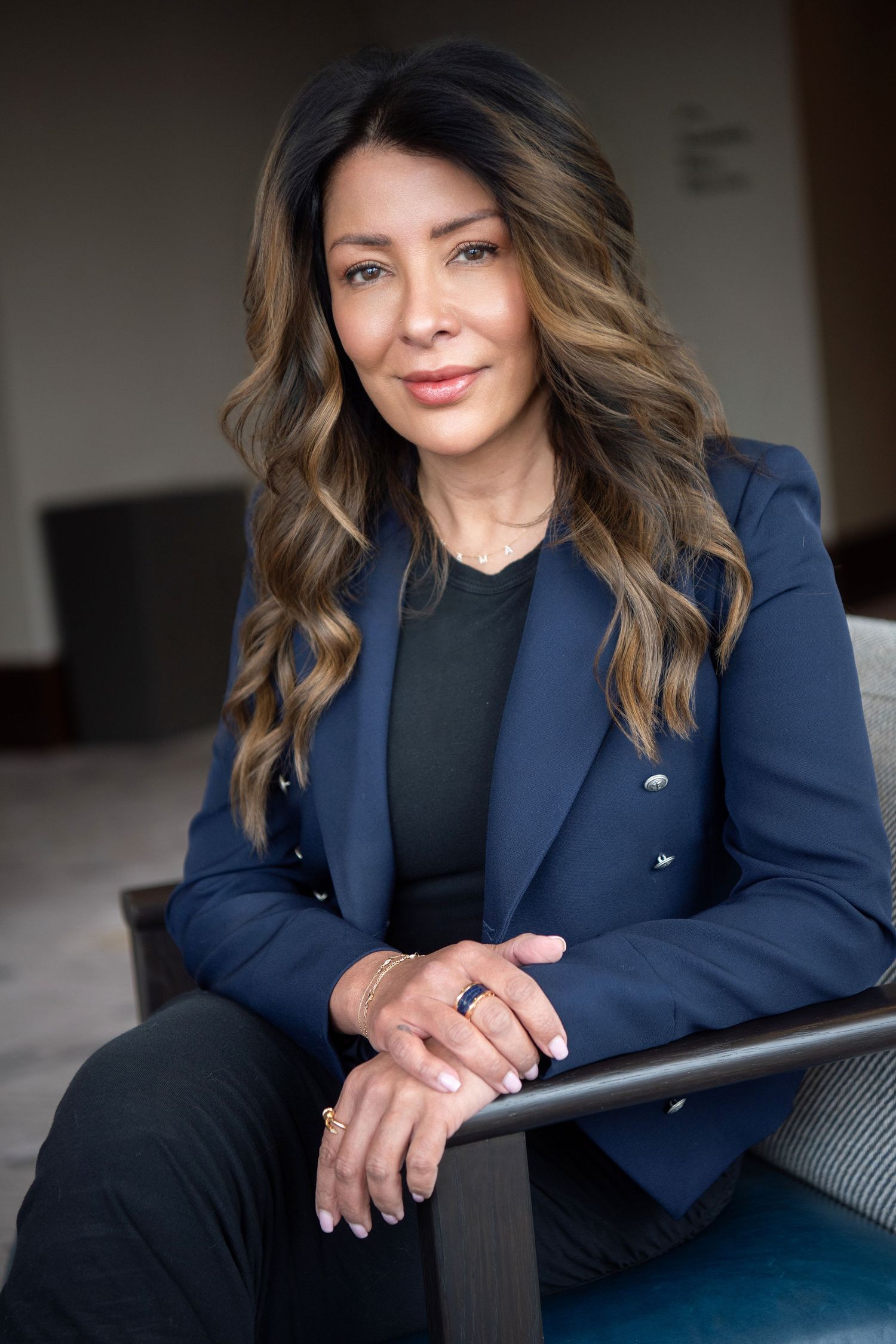 Professional woman in black blazer and beige turtleneck shown in multiple poses against blurred background.