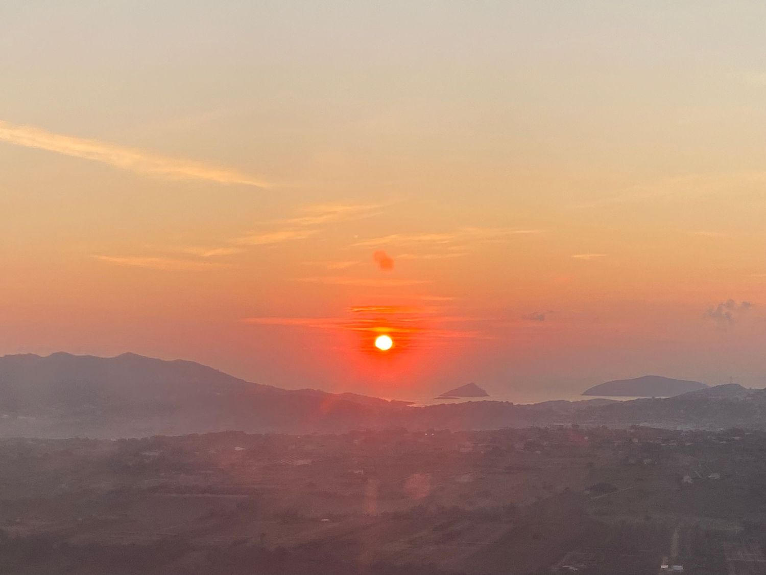 A stunning panoramic view of a mountain landscape at sunset with vibrant orange and red hues in the sky.