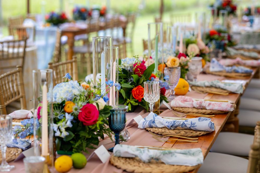 Elegant wedding reception table with colorful floral centerpieces, taper candles, gold chargers, and vibrant blooms.