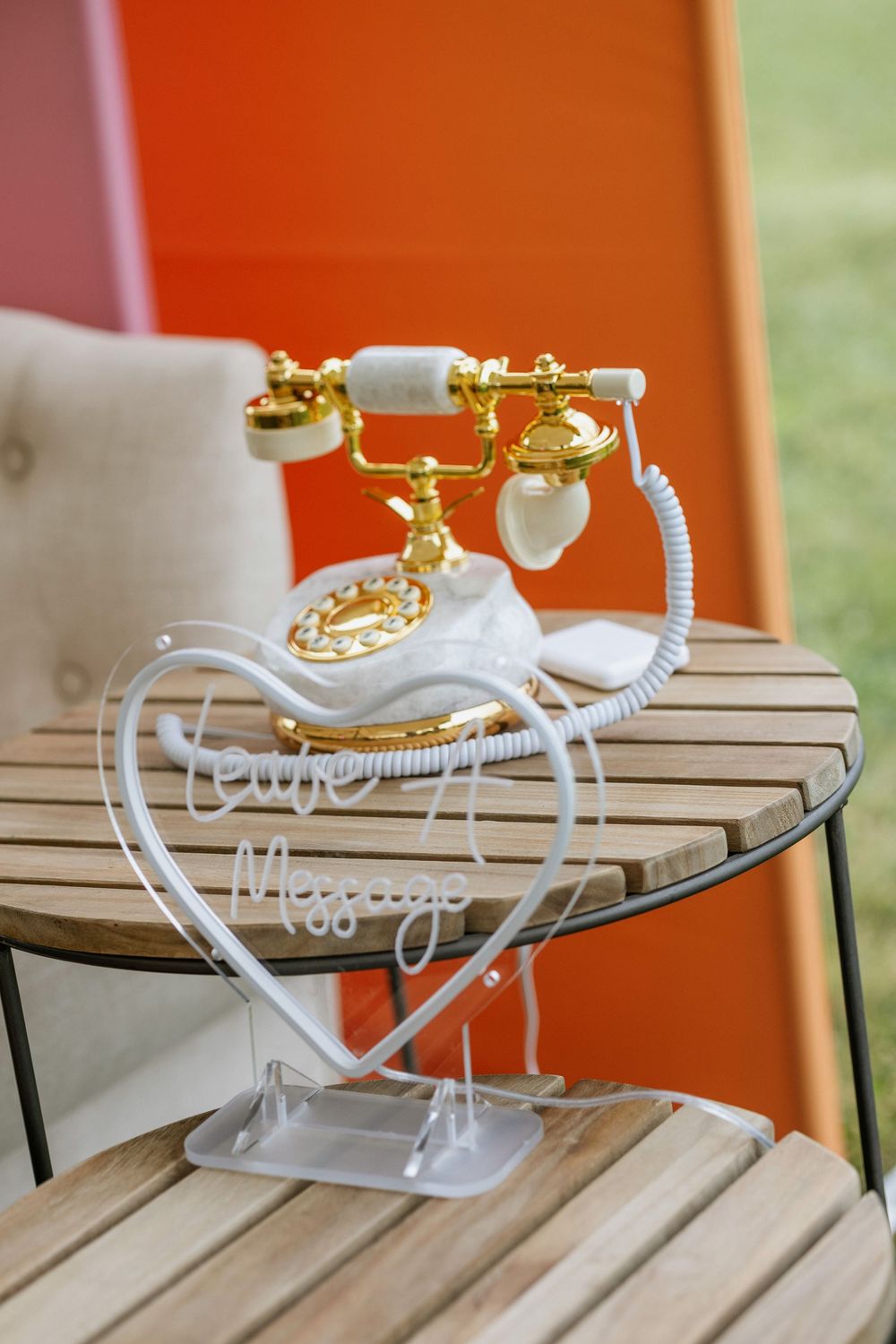 Vintage white and gold rotary telephone on wooden table with heart-shaped neon sign reading Your Message at wedding.
