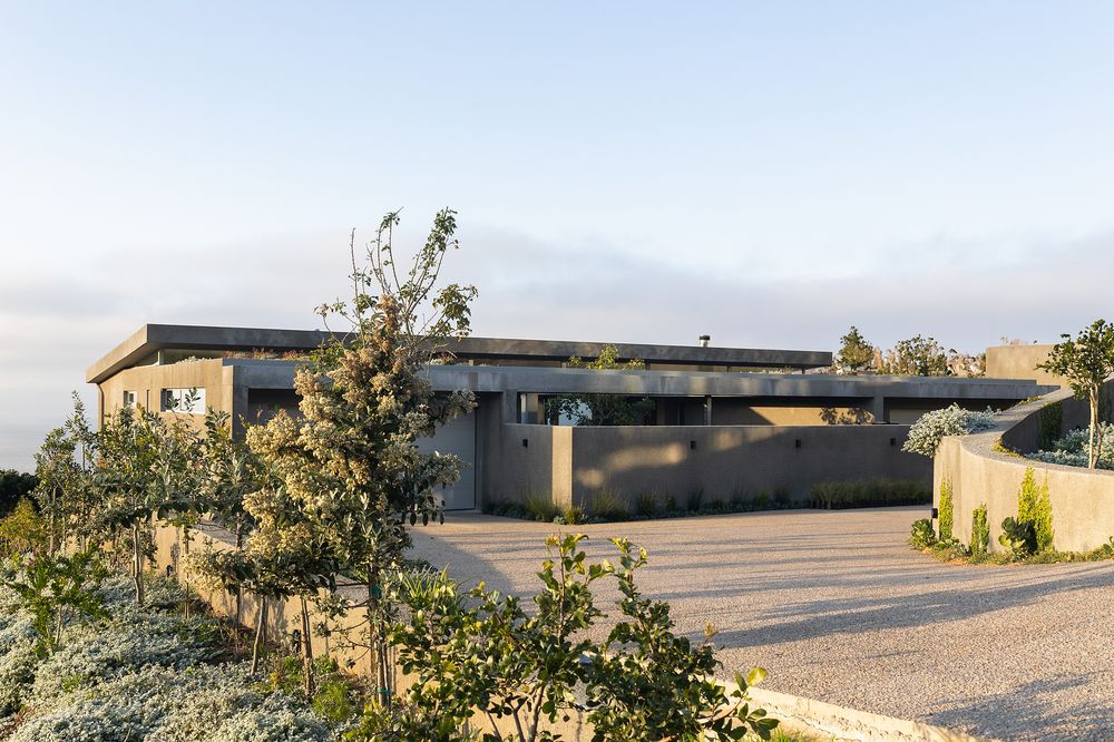 Exterior of a modern beachside house surrounded by greenery and overlooking the coastline