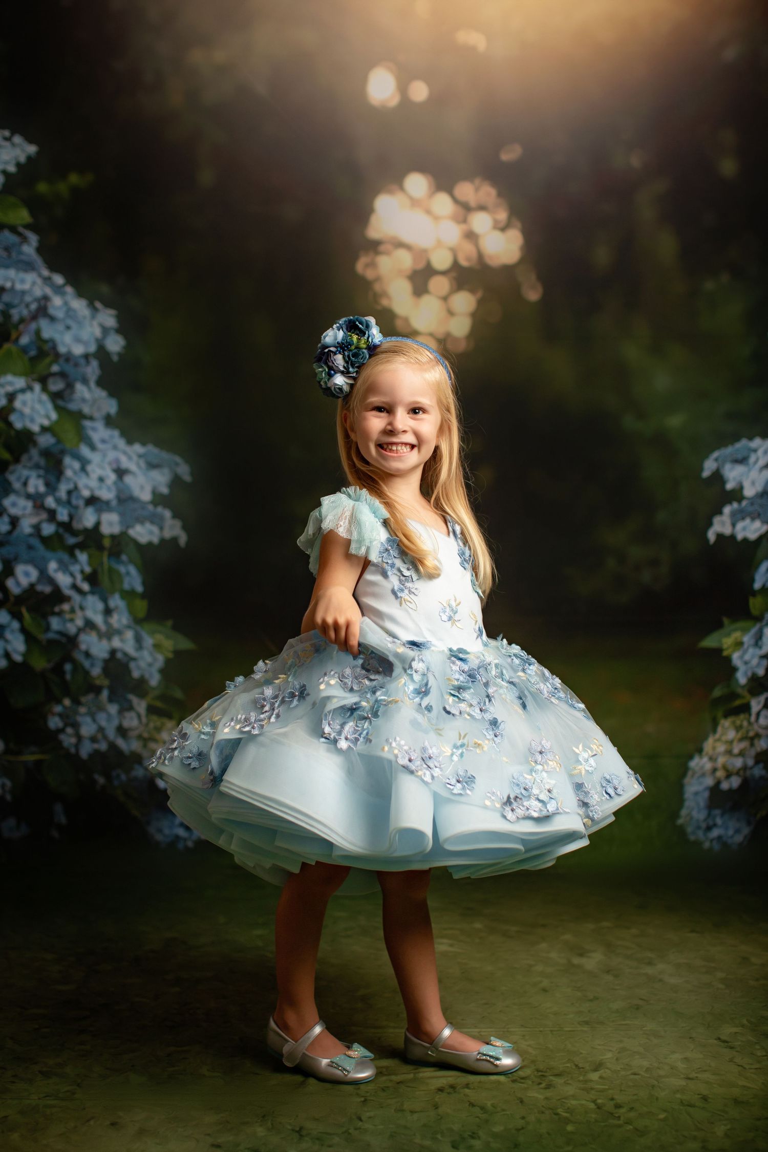 A whimsical garden portrait featuring a light blue dress with floral accents among blooming flowers.