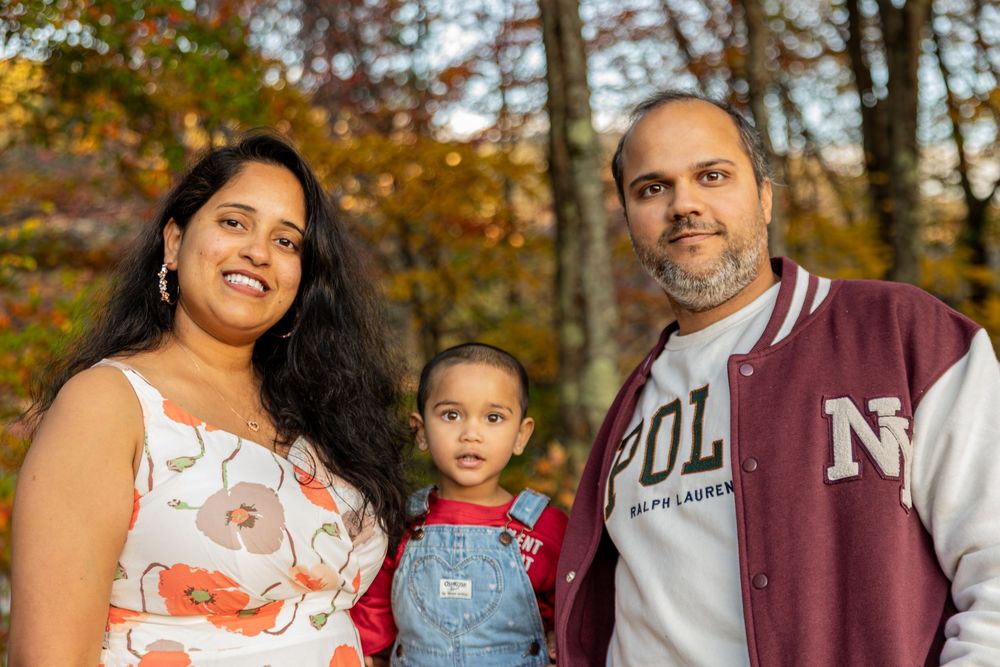 Family enjoying a fall photoshoot outdoors with autumn foliage in the background.