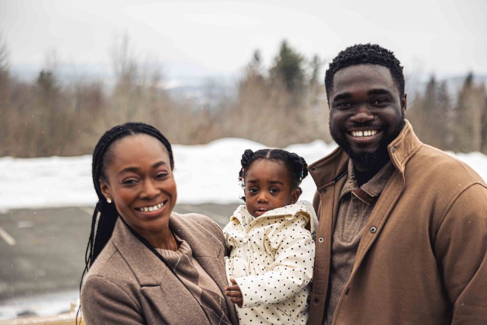 A happy family laughs and plays together in the snow during a winter photoshoot outdoors.