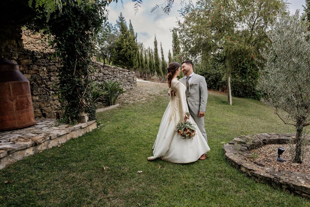 A bride and groom share a romantic kiss in a lush garden setting during their outdoor wedding ceremony.