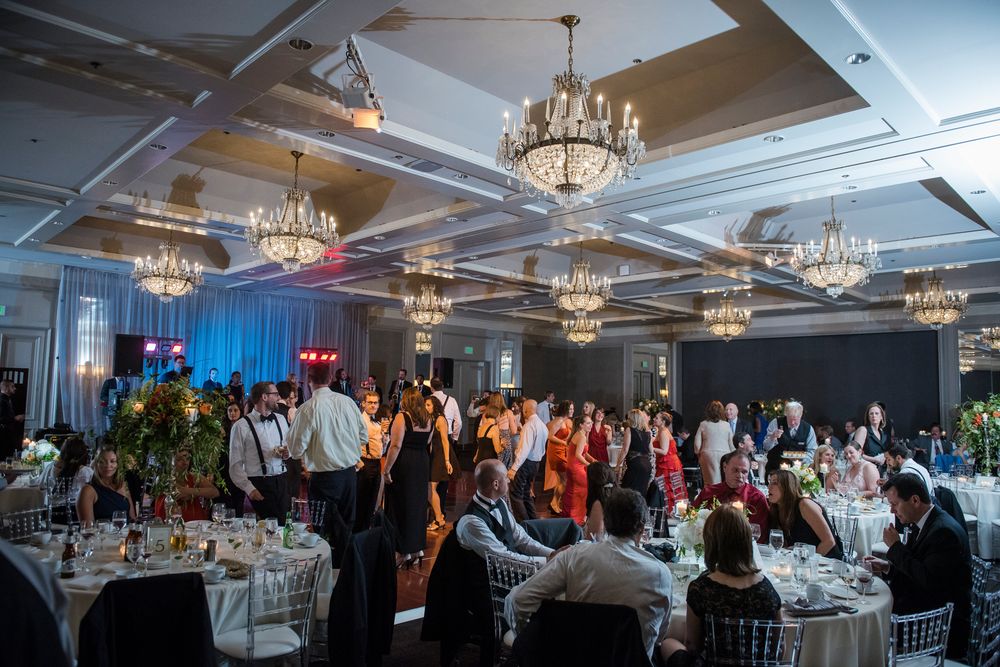 Elegant banquet hall with crystal chandeliers and white table settings during an evening event.